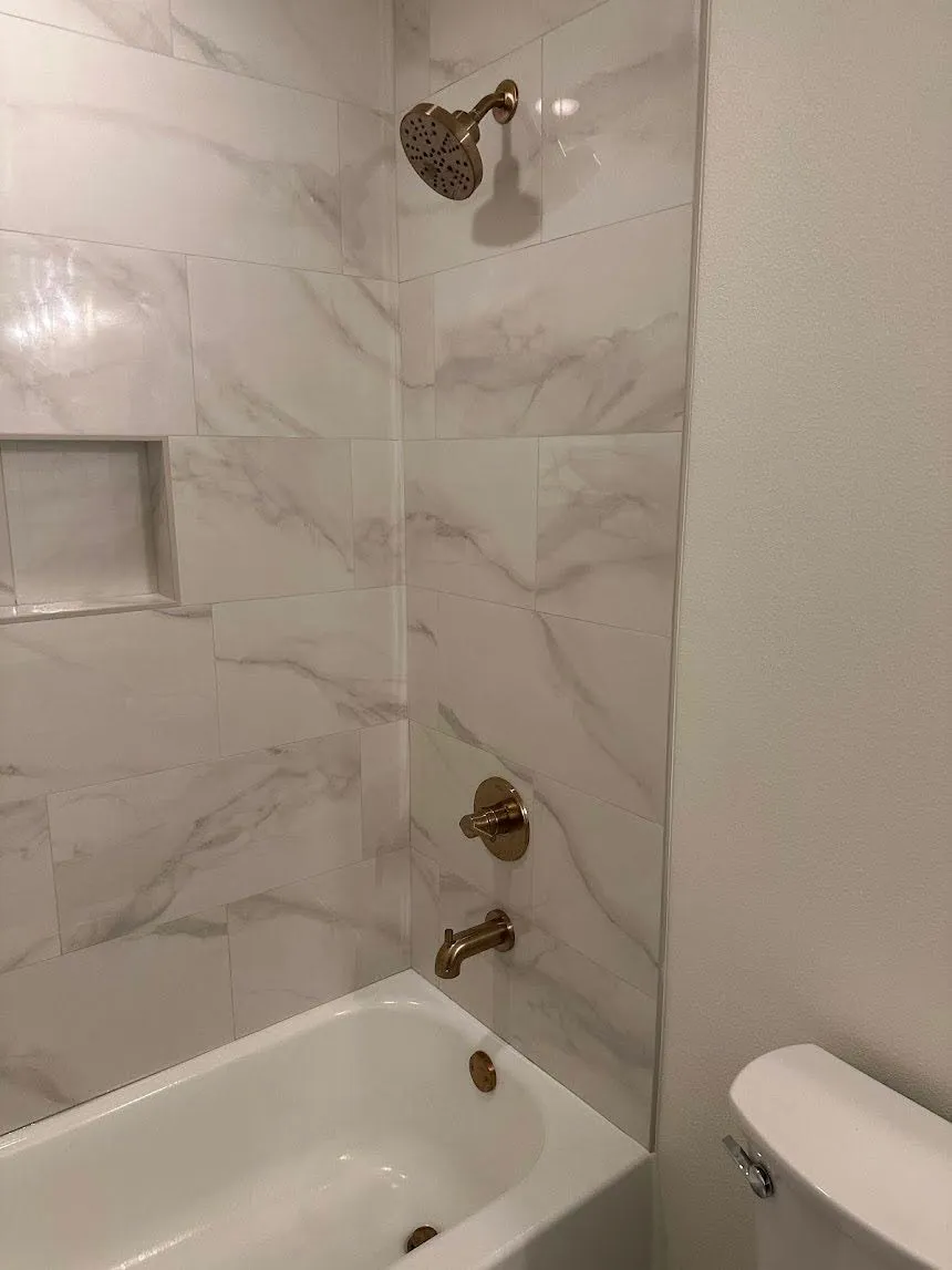 New bathtub and shower fixture installation with brushed bronze trim